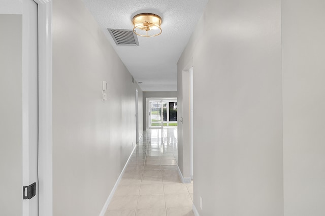 hall featuring a textured ceiling and light tile patterned floors