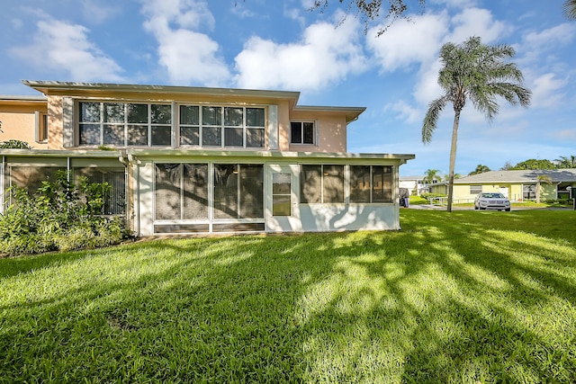 back of house featuring a lawn and a sunroom