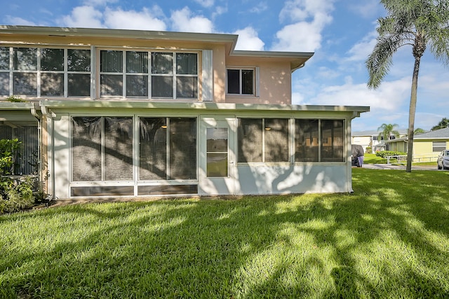 back of property featuring a sunroom and a lawn