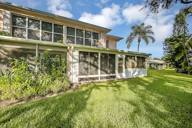 rear view of house featuring a lawn and a sunroom