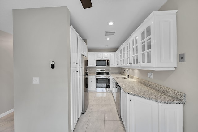 kitchen with light stone counters, light tile patterned flooring, sink, white cabinetry, and appliances with stainless steel finishes