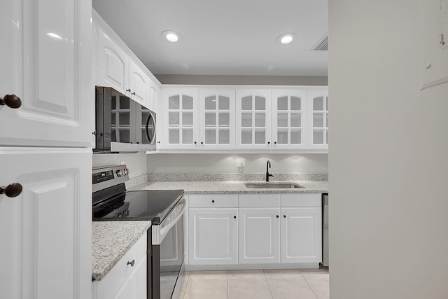 kitchen featuring light tile patterned floors, white cabinets, stainless steel appliances, and sink