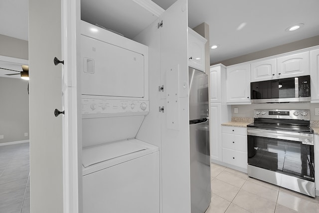 kitchen with white cabinetry, stainless steel appliances, light tile patterned floors, ceiling fan, and stacked washer and clothes dryer