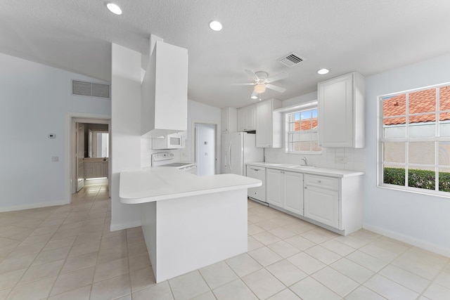 kitchen featuring plenty of natural light, white cabinetry, white appliances, and kitchen peninsula