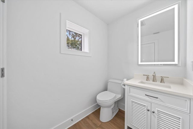 bathroom featuring toilet, baseboards, wood finished floors, and vanity