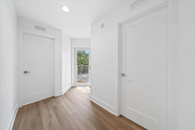hallway with visible vents, recessed lighting, baseboards, and wood finished floors