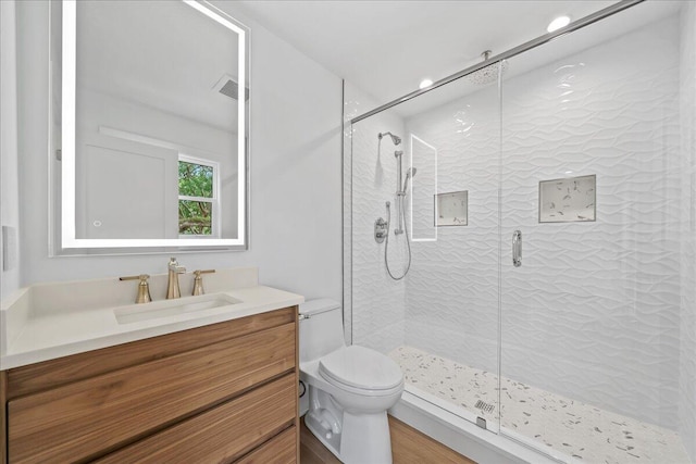 bathroom with hardwood / wood-style floors, a shower with door, toilet, and vanity