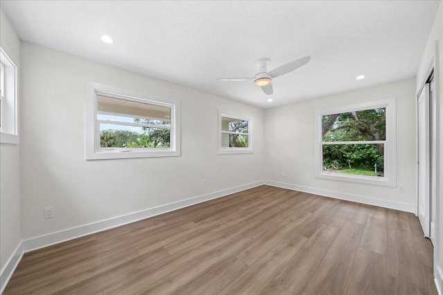 unfurnished room with ceiling fan, a textured ceiling, light hardwood / wood-style flooring, and a healthy amount of sunlight