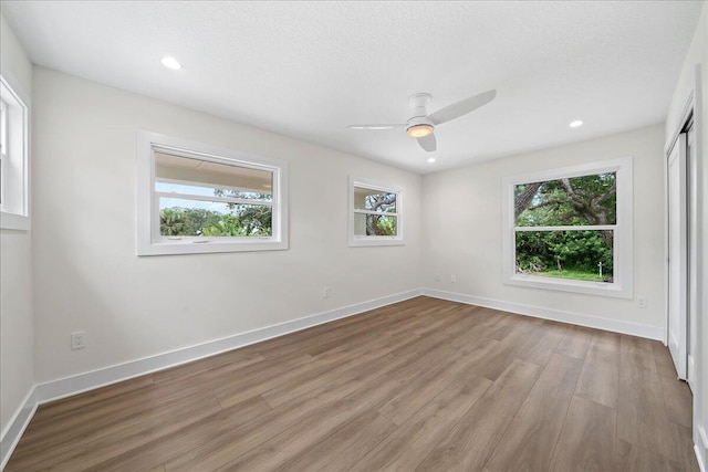 unfurnished room featuring baseboards, light wood finished floors, ceiling fan, and a healthy amount of sunlight