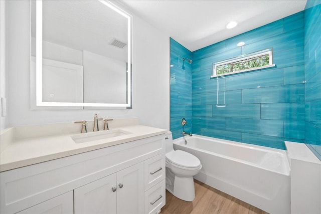 bathroom with visible vents, shower / tub combination, wood finished floors, vanity, and toilet