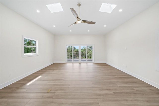 unfurnished room featuring recessed lighting, a skylight, baseboards, and light wood-type flooring