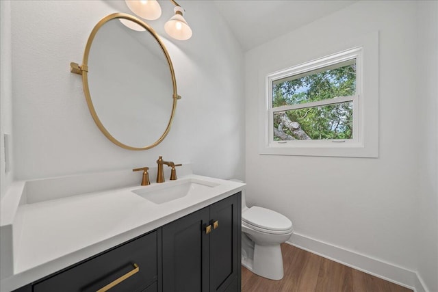 bathroom with wood-type flooring, vanity, toilet, and vaulted ceiling