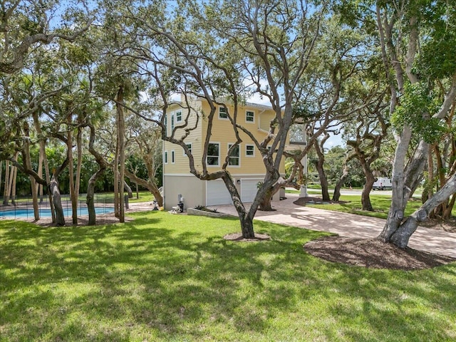 exterior space featuring an attached garage, an outdoor pool, a yard, and driveway