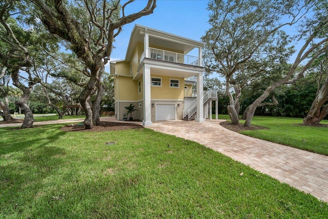 raised beach house featuring a balcony, a garage, and a front lawn