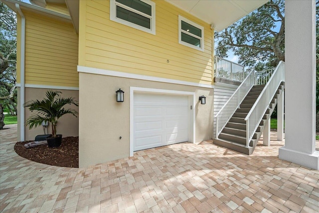 view of side of home featuring stairs, a garage, and stucco siding