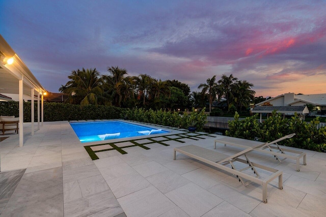 pool at dusk with a patio area