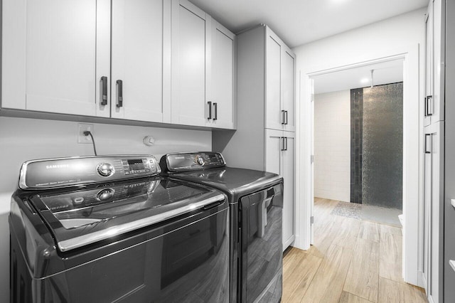 clothes washing area featuring light hardwood / wood-style floors, cabinets, and separate washer and dryer