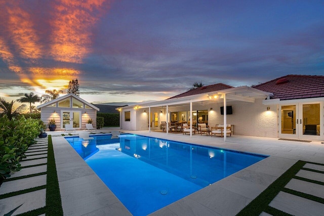 pool at dusk featuring a patio area