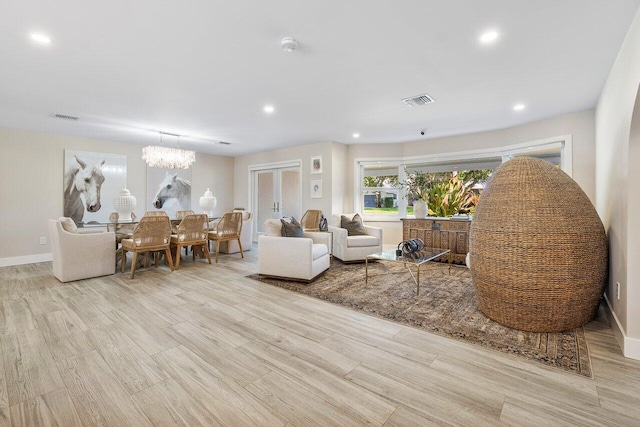 living room with light hardwood / wood-style flooring and an inviting chandelier