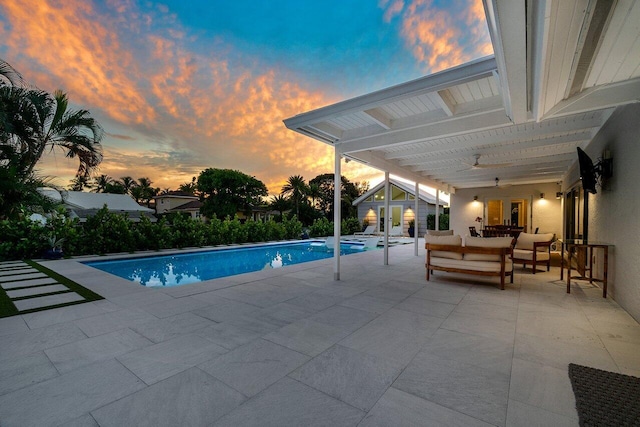 pool at dusk with outdoor lounge area and a patio