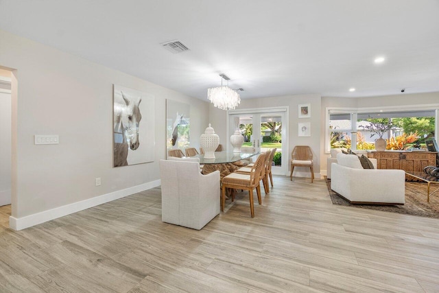 dining area featuring french doors, a notable chandelier, and light hardwood / wood-style flooring