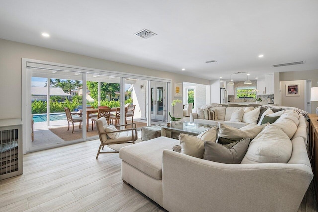 living room featuring french doors, plenty of natural light, and light wood-type flooring