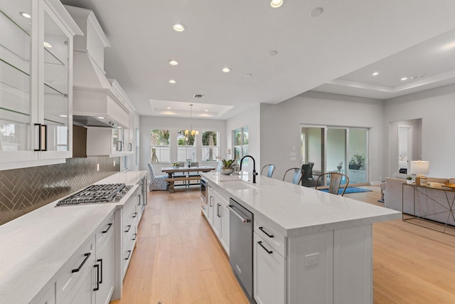 kitchen featuring an island with sink, sink, white cabinets, appliances with stainless steel finishes, and light hardwood / wood-style floors