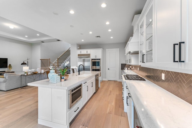 kitchen featuring white cabinets, light hardwood / wood-style flooring, stainless steel appliances, sink, and a center island