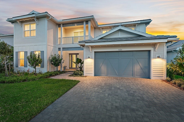 view of front of property featuring a lawn, a balcony, and a garage