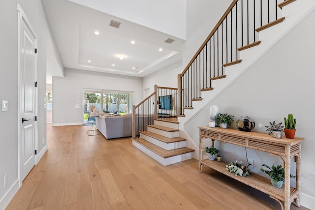 stairs with wood-type flooring and a raised ceiling