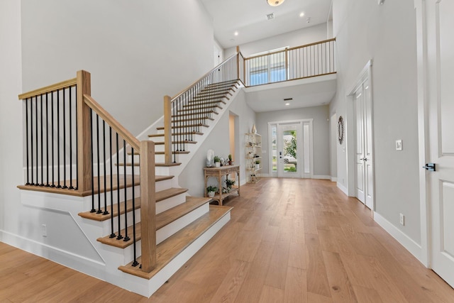 entryway featuring a towering ceiling and light wood-type flooring