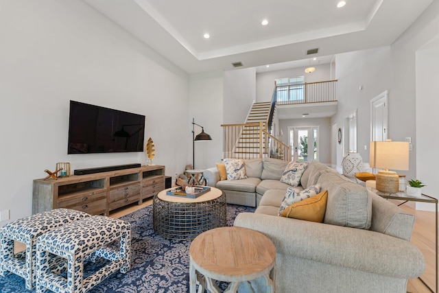 living room with a raised ceiling, wood-type flooring, and a high ceiling