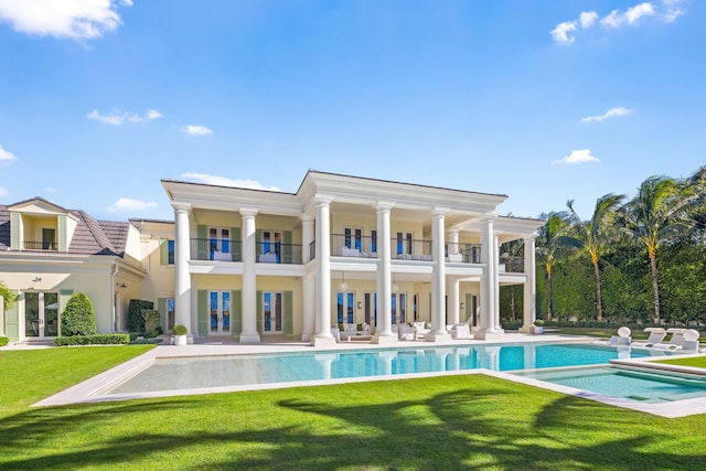 back of house featuring a patio, a yard, a swimming pool with hot tub, and a balcony