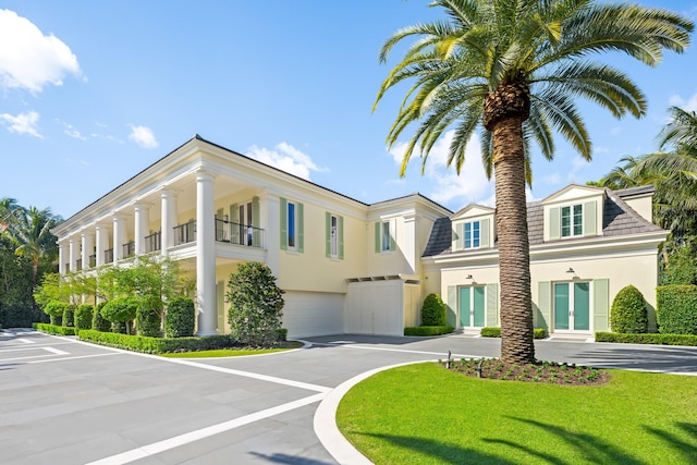 view of front of home with a garage, a front yard, and a balcony