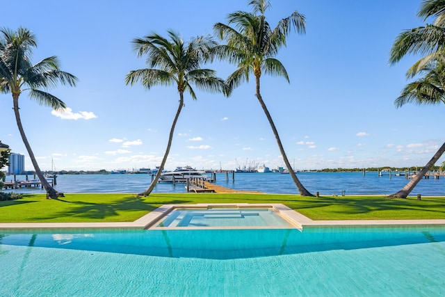 view of swimming pool with a yard, a water view, and an in ground hot tub