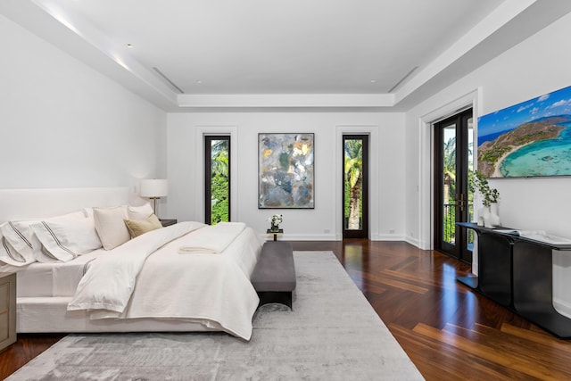 bedroom with access to outside, dark parquet floors, and a raised ceiling