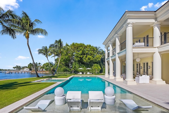 view of swimming pool featuring a water view, a patio, and a yard