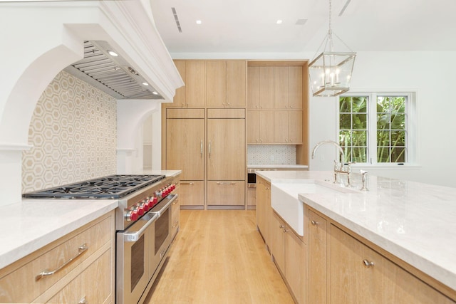 kitchen with sink, light brown cabinetry, high end appliances, and decorative backsplash