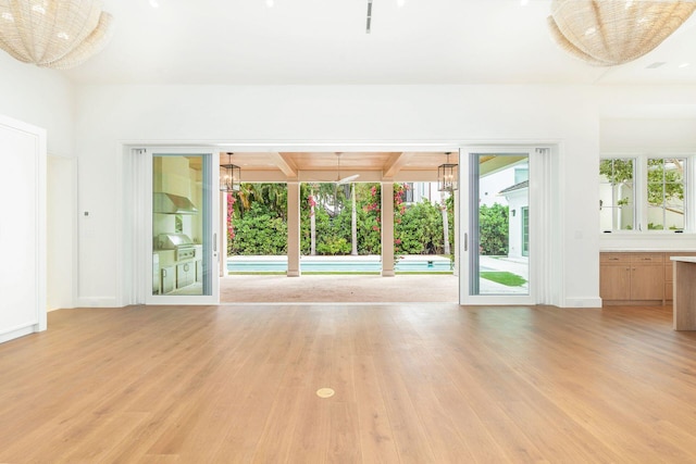 unfurnished living room with light hardwood / wood-style flooring and beamed ceiling