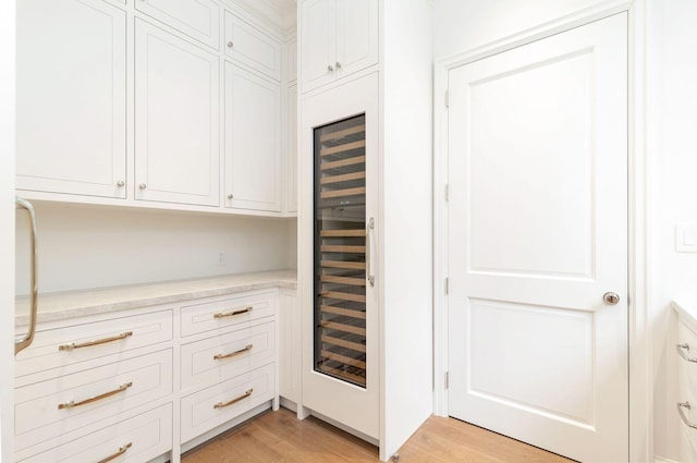 kitchen with white cabinets, beverage cooler, and light hardwood / wood-style floors