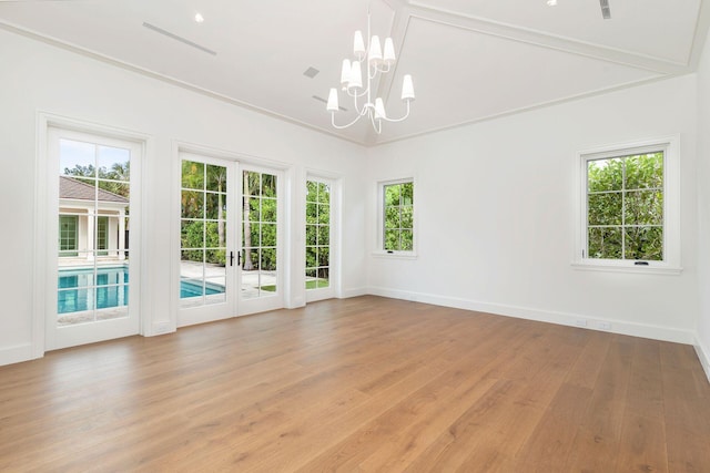 empty room with french doors, light hardwood / wood-style flooring, an inviting chandelier, and ornamental molding