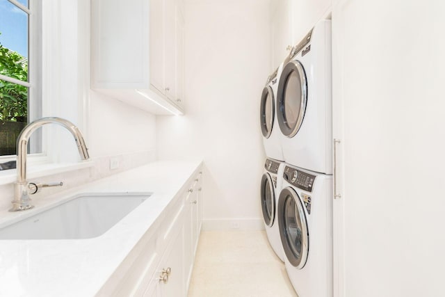 washroom featuring cabinets, stacked washer and clothes dryer, and sink