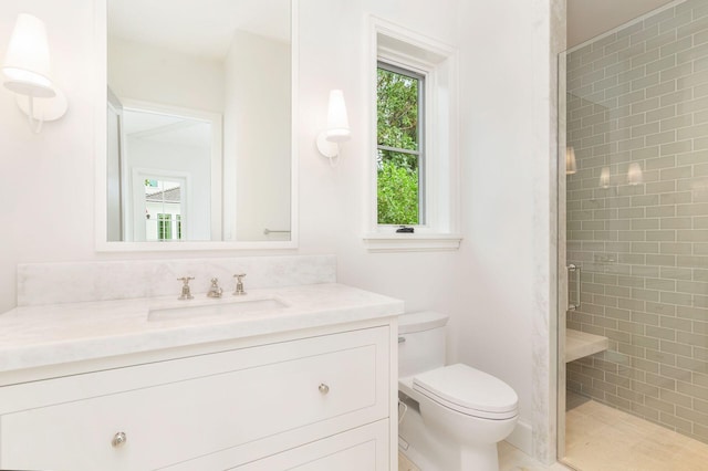 bathroom with toilet, a shower with door, a wealth of natural light, and vanity