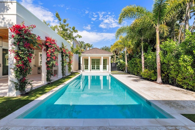 view of swimming pool featuring a patio and an outbuilding