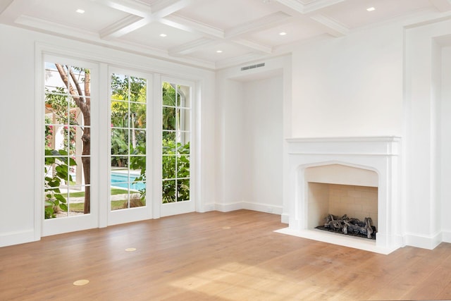 unfurnished living room with coffered ceiling, light wood-type flooring, and beamed ceiling