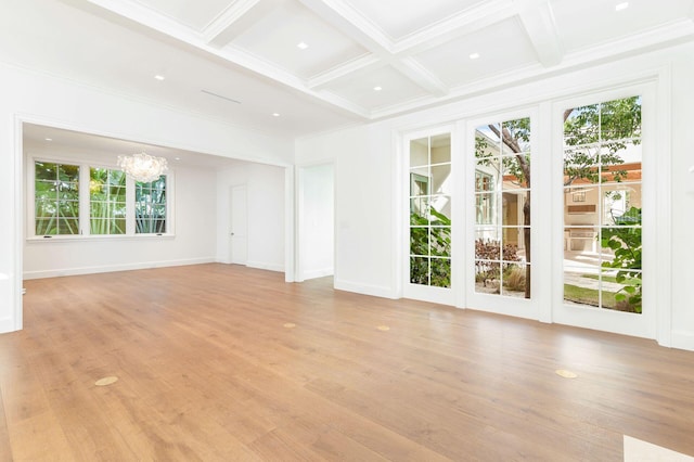 empty room featuring beam ceiling, a healthy amount of sunlight, coffered ceiling, and an inviting chandelier