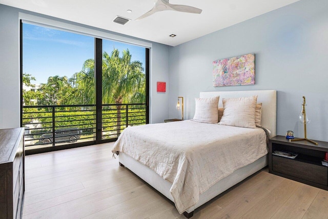 bedroom with light hardwood / wood-style flooring, a wall of windows, and ceiling fan