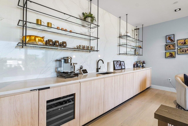 bar featuring sink, beverage cooler, light brown cabinets, and light wood-type flooring