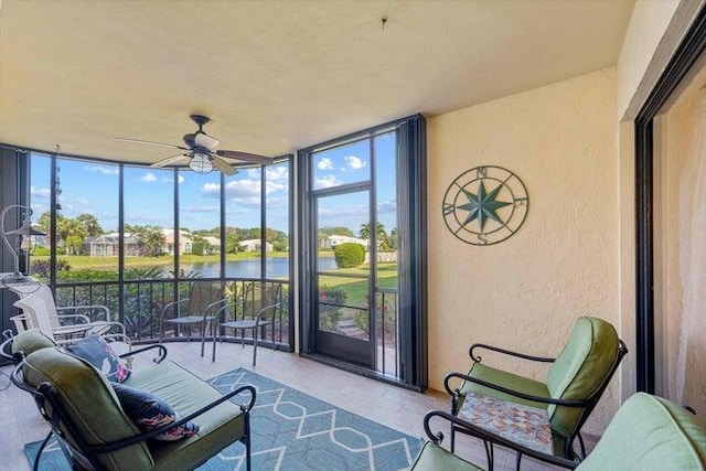 sunroom featuring ceiling fan and a water view