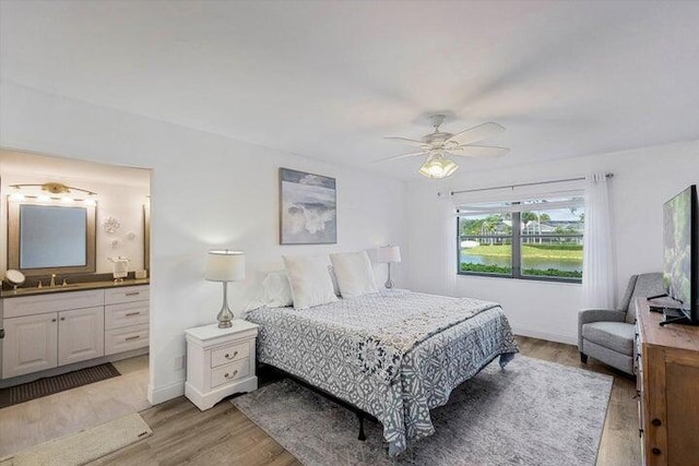 bedroom with ensuite bath, ceiling fan, sink, and light hardwood / wood-style floors